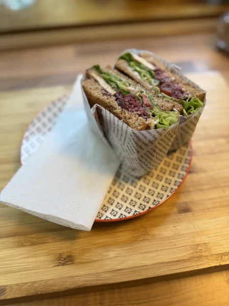 自家製の豆腐、レタス、トマト、ザワークラウトが入ったTLTサンドイッチの写真。